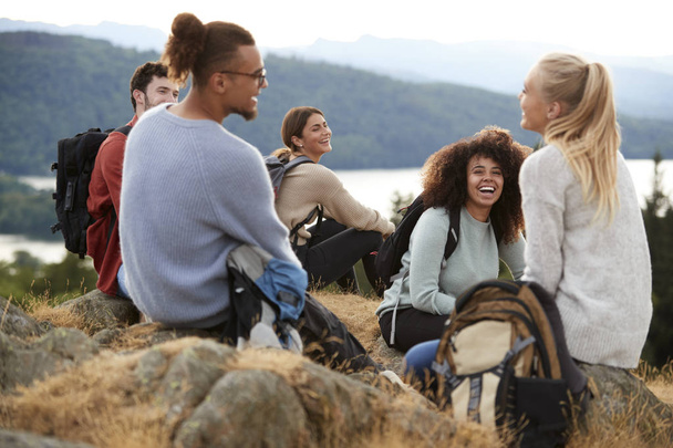 Five young adult friends siting and talking at the summit after a mountain hike - Foto, immagini