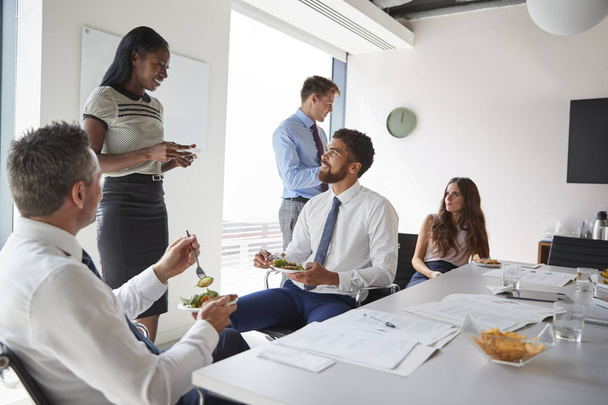 Businessmen And Businesswomen Meeting In Modern Boardroom Over Working Lunch - 写真・画像