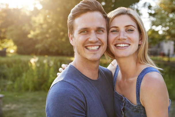 Portrait Of Smiling Couple Outdoors In Summer Park Against Flaring Sun - Foto, imagen