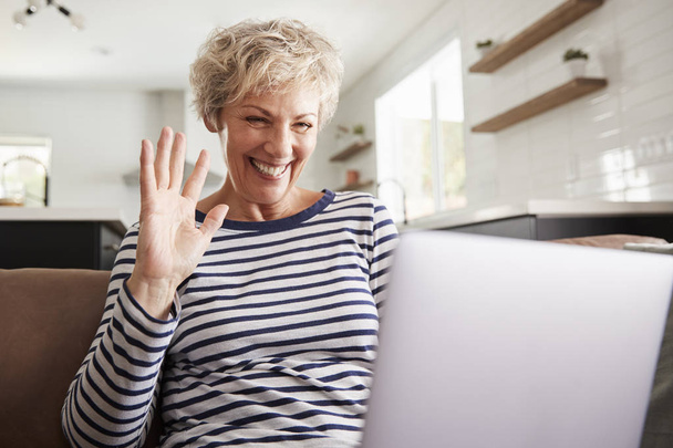 Senior woman video calling on a laptop, waving at screen - Fotoğraf, Görsel