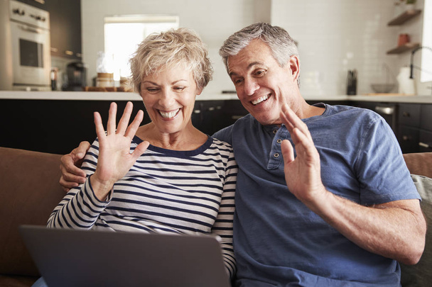 Senior couple video calling on a laptop waving at screen - Foto, afbeelding