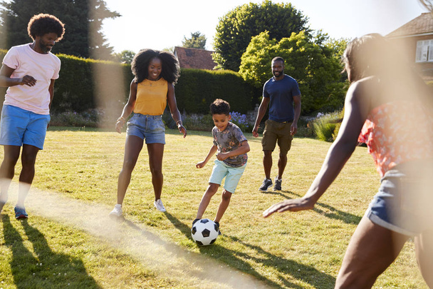 Adult family playing football with young son in garden - Foto, Bild