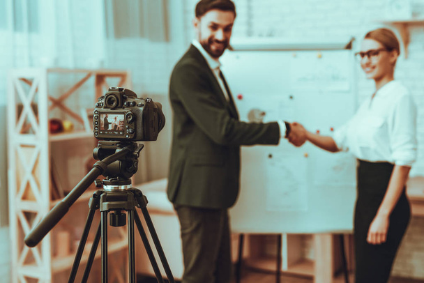 Blur of Bloggers Makes a Video. Bloggers is Businessman and Businesswoman. Video About a Business. Camera Shoots a Video. Businessman and Businesswoman is Handshaking. Business Graph. Studio Interior. - 写真・画像