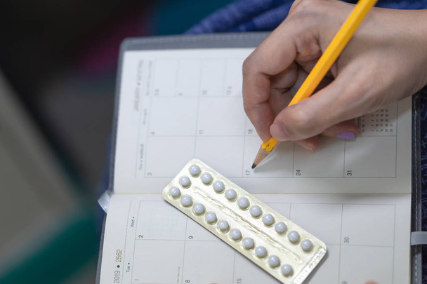 Pille zur oralen Verhütung mit der Hand der Frau Schreibplan, Blasen von Antibabypillen. Abtreibungskonzept. - Foto, Bild