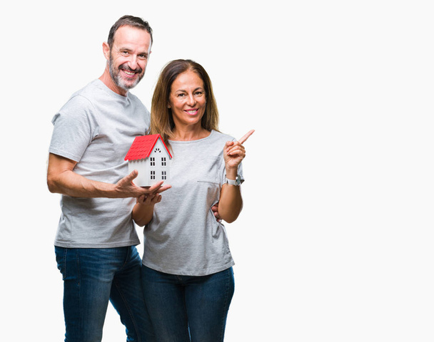 Middle age hispanic casual couple buying new house over isolated background very happy pointing with hand and finger to the side - Fotografie, Obrázek