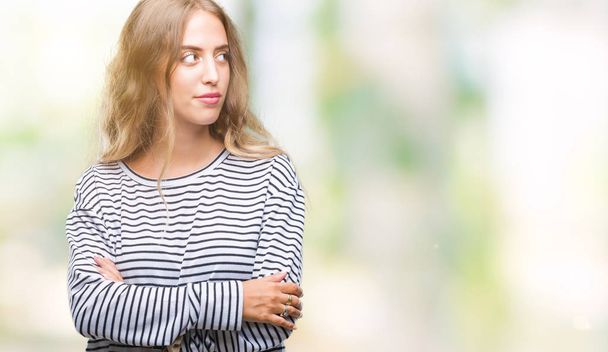 Beautiful young blonde woman wearing stripes sweater over isolated background smiling looking side and staring away thinking. - Photo, Image