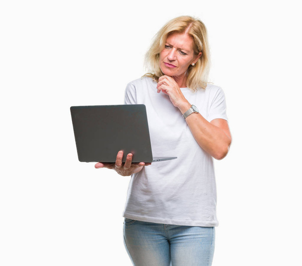 Блондинка средних лет с помощью компьютера ноутбука на изолированном фоне серьезное лицо, думая о вопросе, очень запутанная идея
 - Фото, изображение