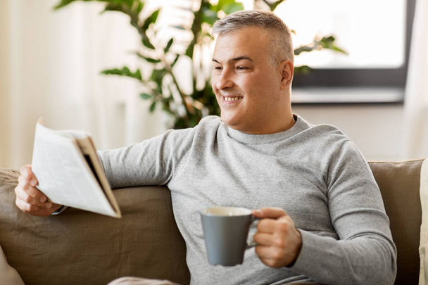 чоловік читає газети і п'є каву вдома
 - Фото, зображення