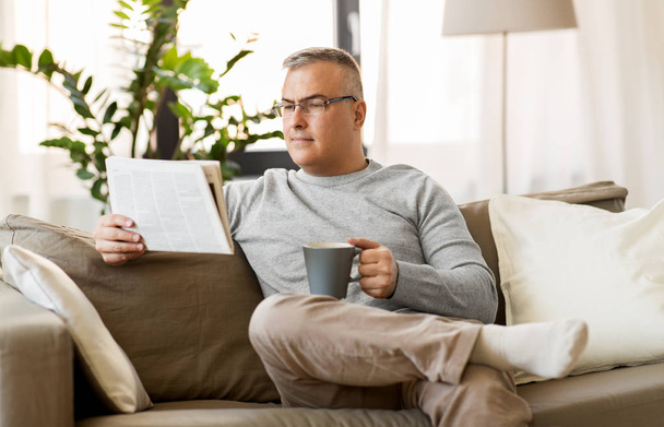 man reading newspaper and drinking coffee at home - Photo, image