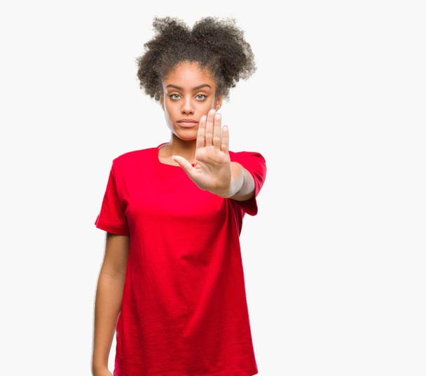 Jonge afro-Amerikaanse vrouw op geïsoleerde achtergrond stop doen zingen met de palm van de hand. Waarschuwing expressie met negatieve en ernstige gebaar op het gezicht. - Foto, afbeelding