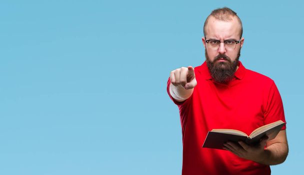 Jeune homme hipster portant des lunettes et lisant un livre sur fond isolé pointant du doigt vers la caméra et vers vous, signe de la main, geste positif et confiant de l'avant
 - Photo, image