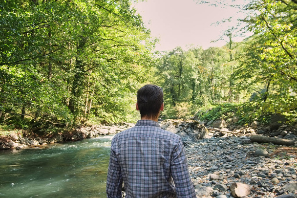 the guy stands and looks at the mountain river. forest area. mountain river. Sochi, Russia - Foto, Bild