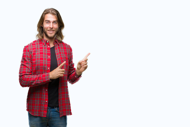 Young handsome man with long hair over isolated background smiling and looking at the camera pointing with two hands and fingers to the side. - Photo, Image