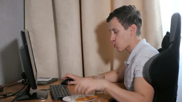 Mann zu Hause isst ein Stück Pizza und spielt am Computer - Filmmaterial, Video