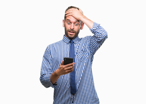 Young hadsome man texting sending message using smartphone over isolated background stressed with hand on head, shocked with shame and surprise face, angry and frustrated. Fear and upset for mistake. - Foto, Bild