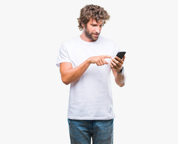 Красива модель іспаномовного чоловіка, що надсилає смс-повідомлення за допомогою смартфона на ізольованому фоні з щасливим обличчям, що стоїть і посміхається з впевненою посмішкою, показуючи зуби
 - Фото, зображення