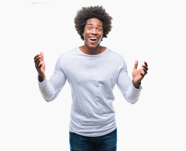 Afro-Amerikaanse man over geïsoleerde achtergrond vieren gekke en gekke voor succes met armen aan de orde gesteld en gesloten ogen opgewonden schreeuwen. Winnaar concept - Foto, afbeelding