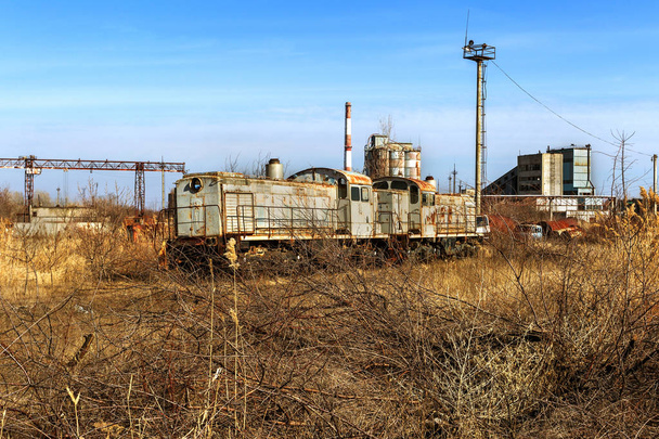 Velha locomotiva enferrujada lançada na zona de exclusão de Chernobyl. Zona de alta radioatividade. Cidade fantasma de Pripyat. Desastre de Chernobil. Rusty abandonou a maquinaria soviética em área de acidente nuclear na fábrica
 - Foto, Imagem