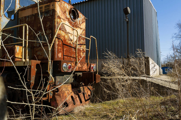 Old rusty train locomotive thrown into exclusion zone of Chernobyl. Zone of high radioactivity. Ghost town of Pripyat. Chernobyl disaster. Rusty abandoned Soviet machinery in area of nuclear accident at plant - Photo, Image