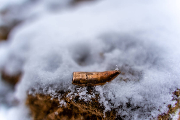 Bent Bullet After Being Shot on the Snowy Sand Background
 - Фото, изображение