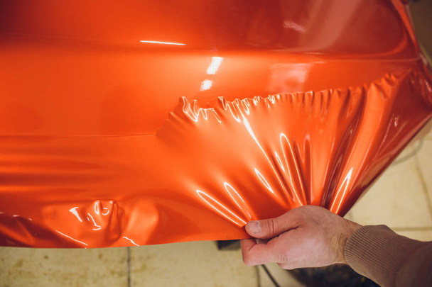 Car wrapping specialist putting vinyl foil or film on car. Selective focus. - Zdjęcie, obraz