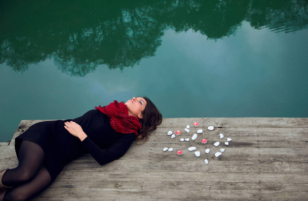 Young woman relaxes on lake pier with blanket - Photo, Image