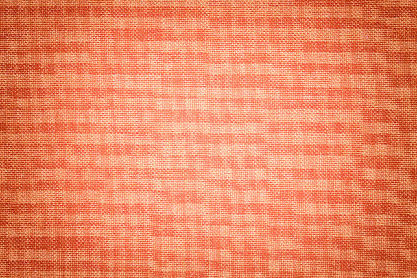 Light coral background from a textile material with wicker pattern, closeup. Structure of the orange fabric with texture. Cloth backdrop with vignette. - Photo, Image