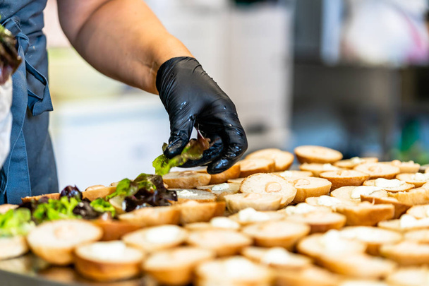 Női szakács elhelyezés összetevők hamburgerek a szeletelt kenyér elterjedt egy asztal - konyhai szett - Fotó, kép