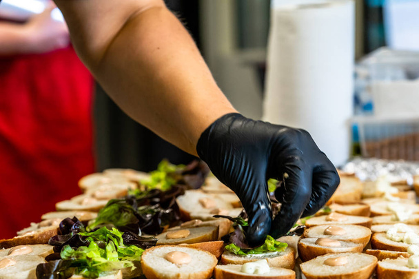 Erkek Chef malzemeler Burger dilimlenmiş ekmek üzerinde koyarak bir masada - mutfak takımı yaymak - Fotoğraf, Görsel
