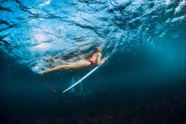 Surfer meisje in bikini met surfplank duik onderwater en Golf - Foto, afbeelding