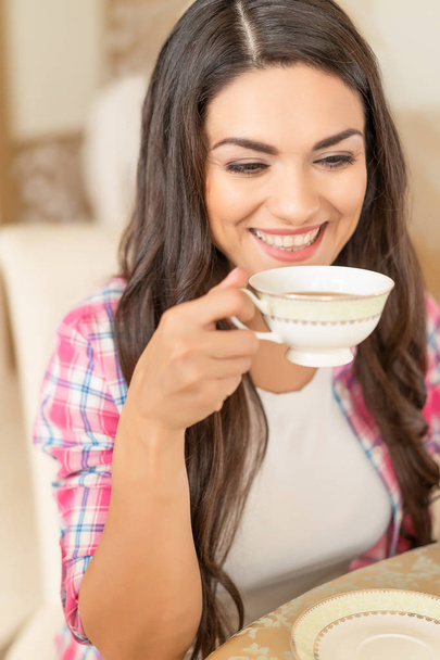 Smiling beautiful brunette drinks a cup of tea. - Fotoğraf, Görsel