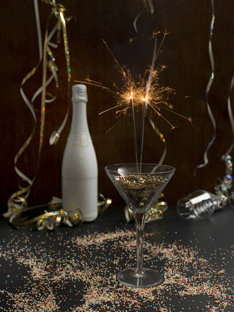 new year background with burning sparklers in glass and champagne bottle with Christmas items on background   - Fotó, kép