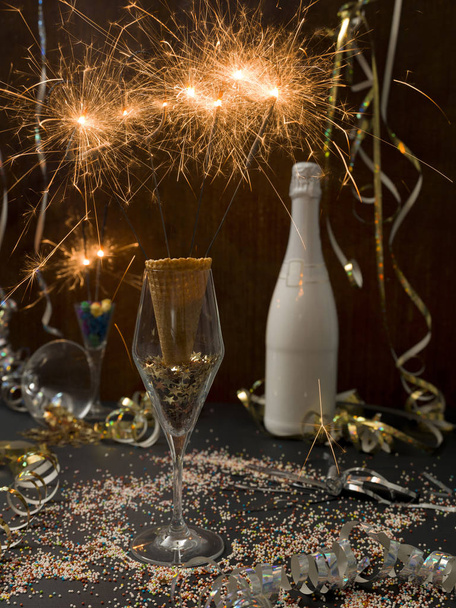 new year background with burning sparklers in glass and champagne bottle with Christmas items on background   - Valokuva, kuva
