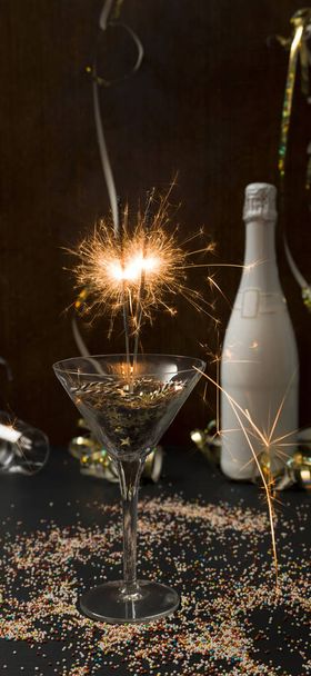 new year background with burning sparklers in glass and champagne bottle with Christmas items on background   - Zdjęcie, obraz