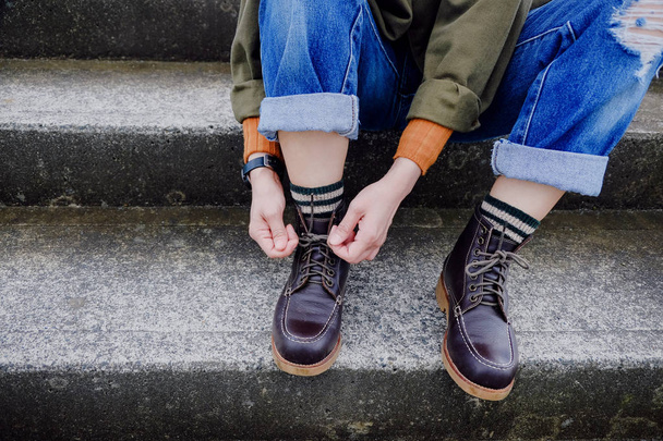 Мода і тканину для осінньо-зимового сезону. Croped зображення для джинси, взуття та шкарпетки. Муніципалітет Hipster жінка краватку шнурки сидячи на сходах - Фото, зображення