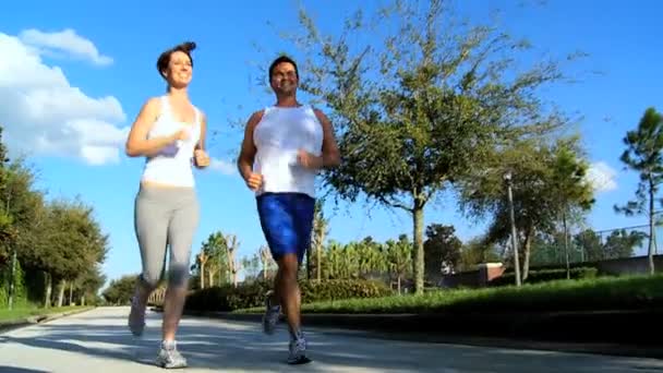 jong koppel joggen op voorstadswegen - Video
