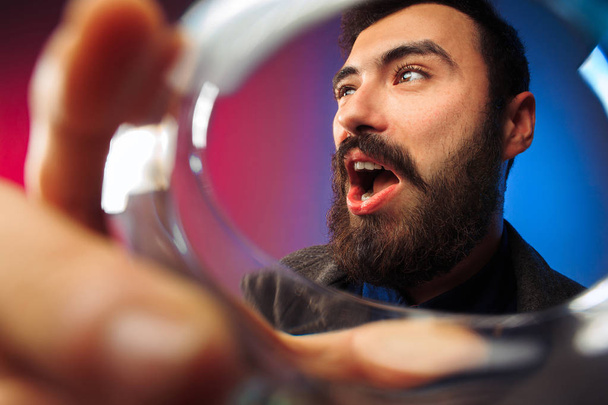 The surprised young man in party clothes posing with glass of wine. - Photo, Image