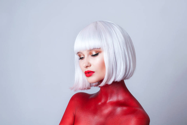 Portrait of young beautiful woman with white hair red lips and red body-art on white background - Photo, Image
