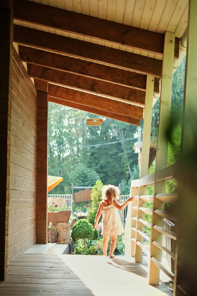 Portrait of a little girl walking outside along the veranda, - Foto, Bild