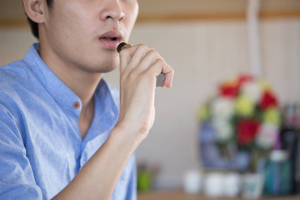 Mavi tişört giyen genç Asyalı adam, tütün ya da sigara dumanıyla nefes ver. - Fotoğraf, Görsel