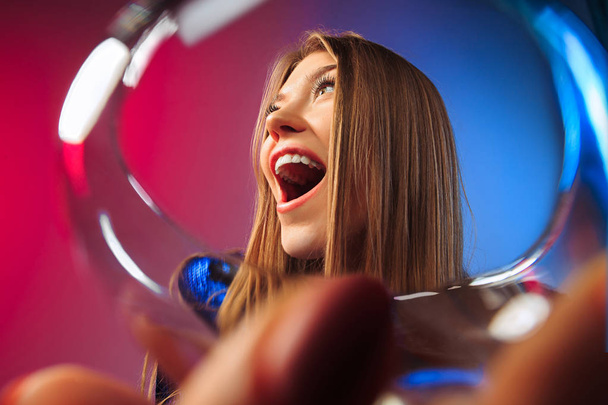 The surprised young woman in party clothes posing with glass of wine. - Foto, Imagem