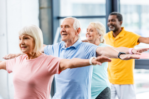 atletas senior multiculturales felices sincrónicos haciendo ejercicio en el gimnasio
 - Foto, Imagen