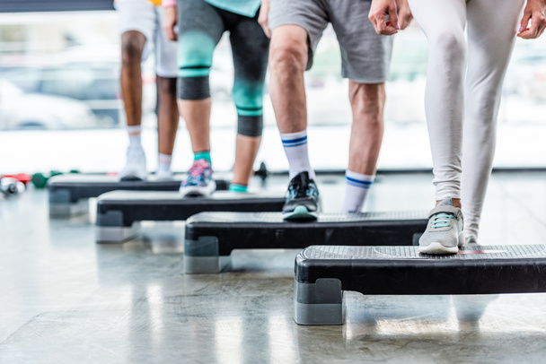 imagen recortada de deportistas haciendo ejercicio en plataformas escalonadas en el gimnasio
 - Foto, Imagen