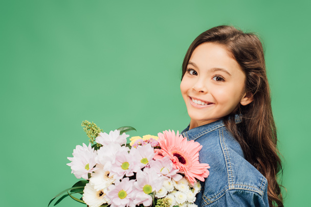 smiling child with flower bouquet looking at camera isolated on green  - Fotoğraf, Görsel