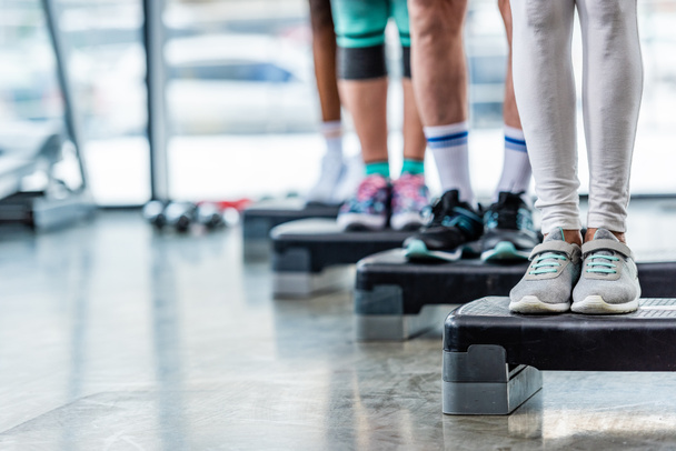 cropped shot of sportspeople standing on step platforms at gym - Foto, Imagen