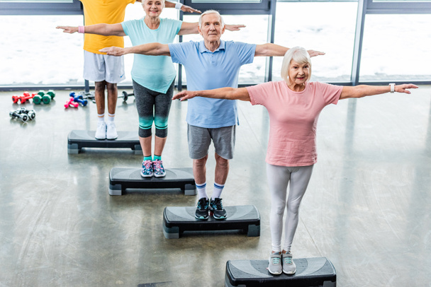 üst düzey sporcuların spor salonunda adım platformlarda egzersiz zaman uyumlu yüksek açılı görünüş - Fotoğraf, Görsel