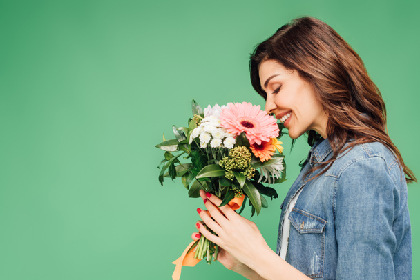 smiling woman holding and sniffing flower bouquet isolated on green - Photo, Image