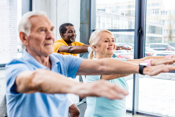 enfoque selectivo de los atletas senior multiculturales síncrona hacer ejercicio en el gimnasio
 - Foto, Imagen