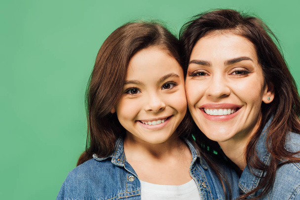 beautiful mother and adorable daughter looking at camera isolated on green - Foto, Imagen