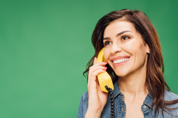 mosolygó gyönyörű nő beszélni, vintage telefonon elszigetelt zöld - Fotó, kép